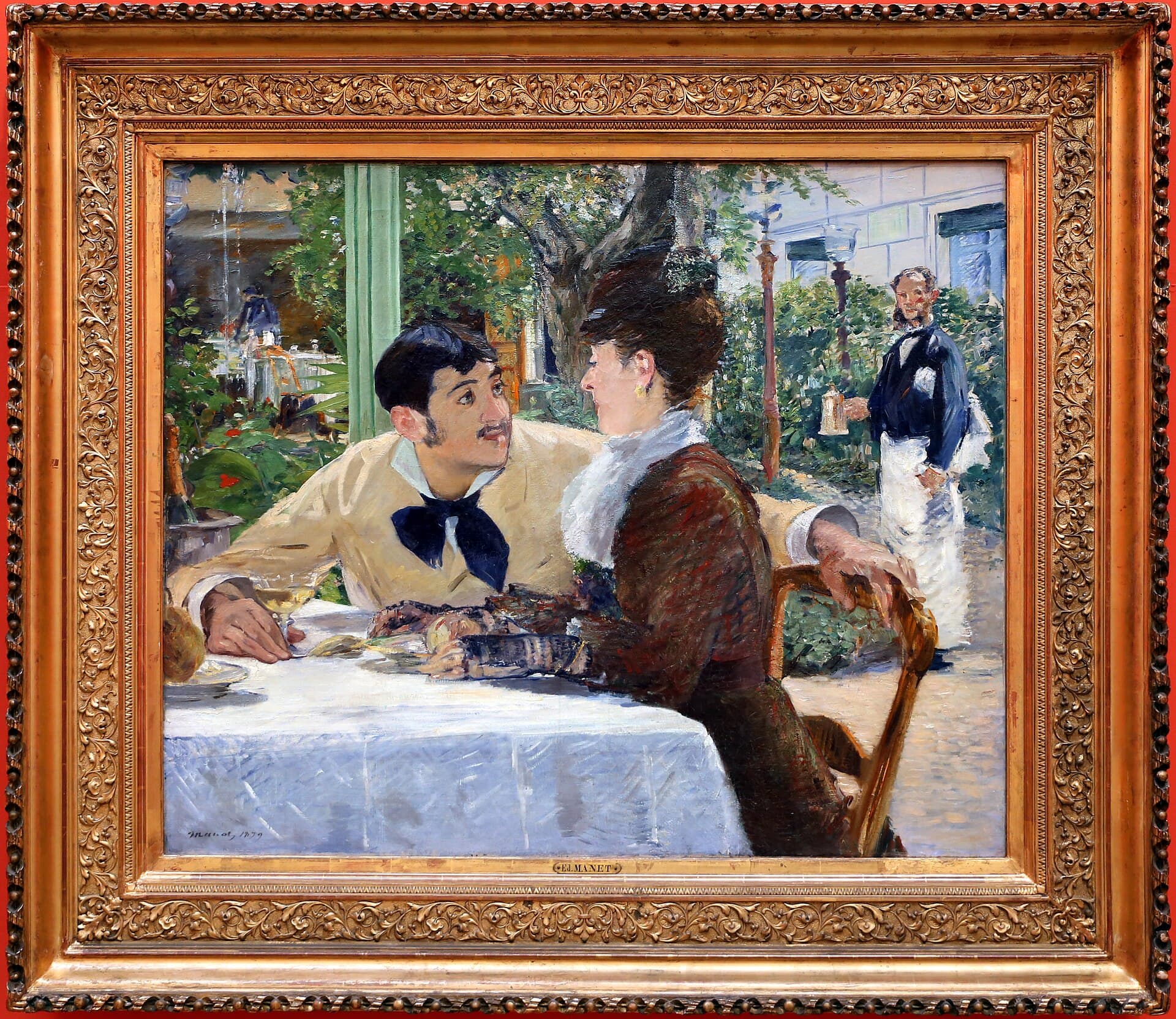 A young man courts a woman at a restaurant table in a sun-dappled garden, a waiter hovering in the background.