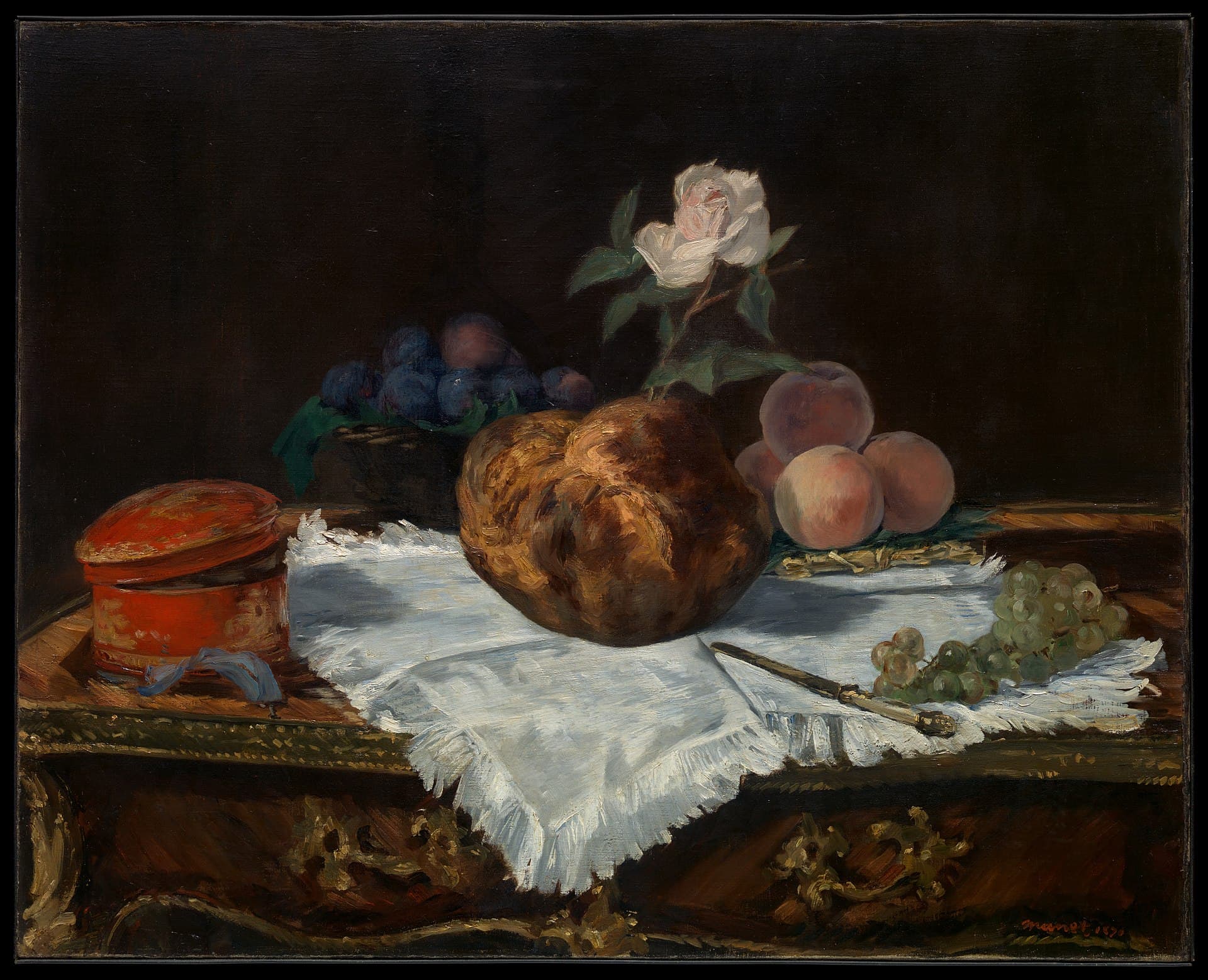 A golden brioche crowned with a sprig of flowers sits on a white cloth beside a lemon and a knife.